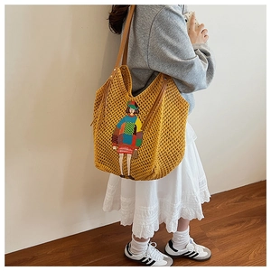 Detail of yellow knit tote bag featuring a cute cartoon girl patch and leather straps