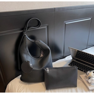 Detailed set of black lychee grain tote bag with laptop and accessories on white bedding