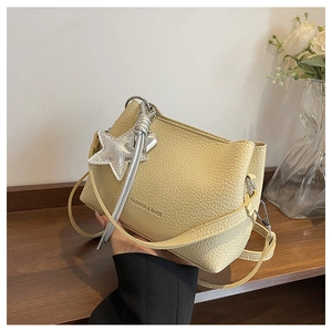 Detail of light yellow lychee pattern leather bucket bag with silver star charm