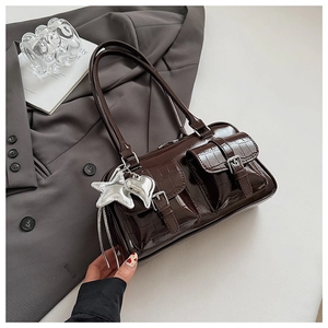 Detailansicht der braunen Kroko-Handtasche mit silbernen Sternanhängern und Schnallentaschen