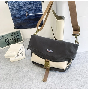 Detail of grey and beige nylon crossbody bag featuring green buckle and adjustable strap