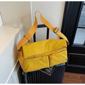 Detail of yellow nylon tote bag with front zipper pockets on a black suitcase