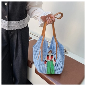 Close-up of light blue crochet tote bag showing detailed embroidery and brown leather handles