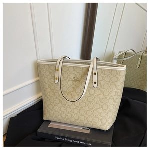 Detail of premium monogram tote bag featuring leather handles on minimalist art books