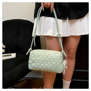 Detail of mint green polka dot handbag featuring B-logo emboss and pearl tassel charm