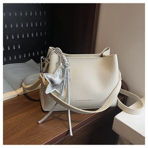 Close-up of cream leather bucket bag with silver star charm and engraved text detail
