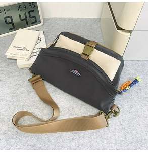 Detail of nylon crossbody messenger bag featuring a buckle strap and a textured finish