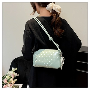 Detail of mint green polka dot crossbody bag with B-letter embossing and pearl tassel