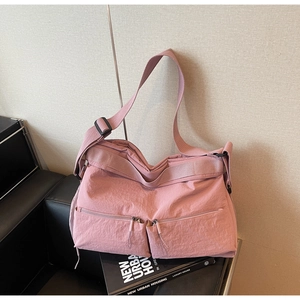 Detail of pink nylon crossbody bag with dual front zipper pockets and wide strap