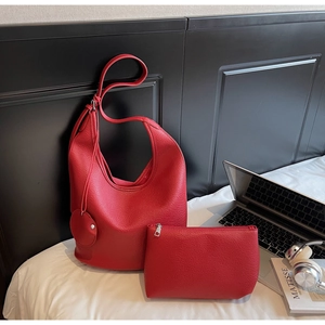 Detailed view of red pebble texture PU leather hobo bag set with matching pouch on bed