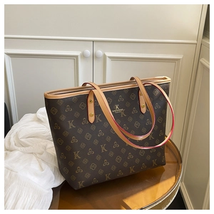 Detailed close-up of dark brown monogram tote bag with gold lettering and leather handle