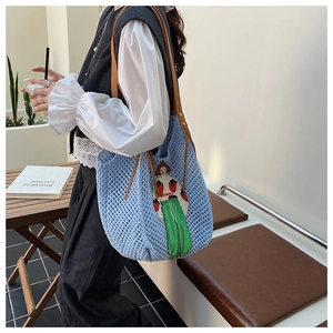 Detail of light blue crochet tote bag featuring a cute cartoon girl patch and leather straps