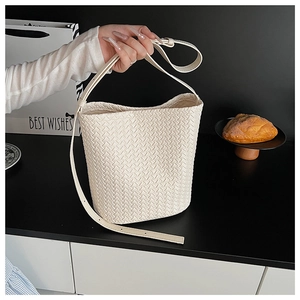 Detailed view of cream woven bucket bag with fine knit texture and adjustable shoulder strap
