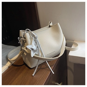 Detail of cream white pebbled leather bag with silver star charm and engraved fashion text