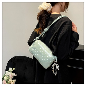 Detail of mint green polka dot bag featuring 3D bow and pearl butterfly pendant