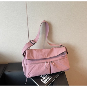 Detail of light pink nylon crossbody bag with multi-pocket design and pleated texture