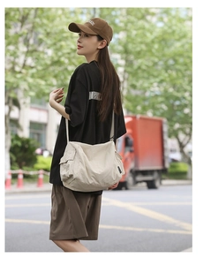 Détail du sac bandoulière en toile beige avec sangle réglable et poche latérale utile
