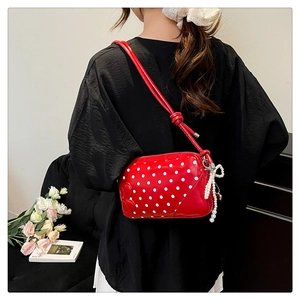 Close-up of red polka dot handbag with 3D B-letter logo and white pearl bow charm