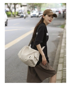 Détail du sac cabas en toile beige avec poche latérale à rabat en milieu urbain chic