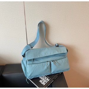 Close-up of light blue multi-pocket nylon crossbody bag with adjustable wide strap