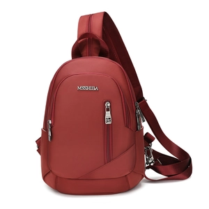 Détail du sac bandoulière en nylon bordeaux montrant le logo métallique et la fermeture