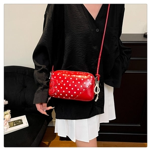 Close-up of red polka dot crossbody bag with a pearl charm and embossed B letter