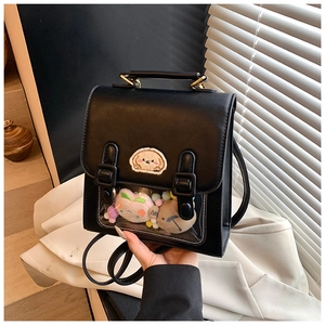 Close-up of black PU leather mini backpack featuring a clear window with colorful plush toys