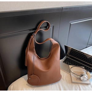 Detailed close-up of brown PU leather hobo bag with litchi texture and round charm