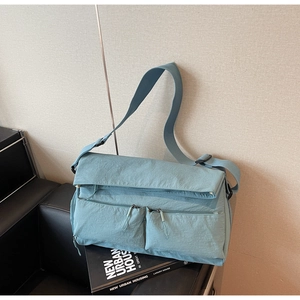 Detail of blue nylon messenger bag with double front pockets and adjustable strap