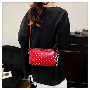 Detail of red polka dot crossbody bag with pearl bow charm and letter B decoration