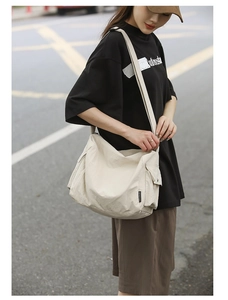 Gros plan du sac bandoulière en toile beige avec poche à rabat et sangle réglable