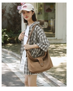 Detail shot of a brown canvas messenger bag with durable fabric and flap buckle closure