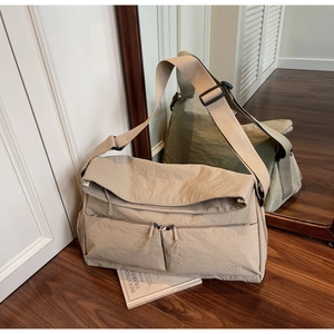Macro shot of beige nylon messenger bag with double zipper pockets and wide shoulder strap