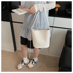 Detailed woven texture of off-white leather bucket bag with adjustable shoulder strap