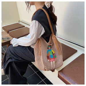 Detail of colorful cartoon embroidery and brown leather handle on a beige knitted tote bag