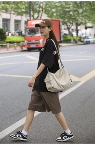 Photo de rue d'un sac bandoulière en toile beige porté par un mannequin au style décontracté