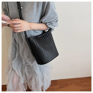 Detail of classic black woven leather bucket bag texture worn crossbody for a trendy look