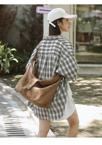 Close-up of brown canvas crossbody bag featuring flap closure and wide shoulder strap