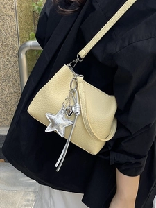 Minimalist yellow bucket bag with star and heart charms worn by model on shoulder