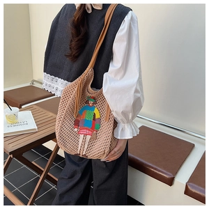 Detail of hand-crocheted tote bag with cartoon patch and brown leather strap
