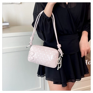 Detail of pink polka dot shoulder bag featuring pearl chain and 3D B-letter detail
