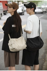 Détail de grands sacs messagers en nylon beige et noir avec poches à rabat