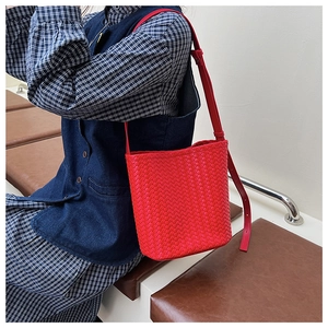 Detail of red woven leather bucket bag featuring intricate cross-braided craftsmanship