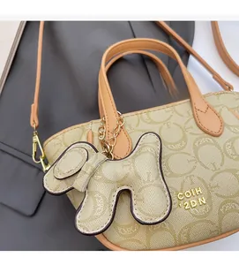 Detail der hellbraunen Handtasche mit Prägemuster und passendem Hundeanhänger-Zubehör