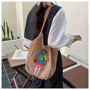 Detail of hand-woven tote bag featuring cartoon embroidery and brown leather handles
