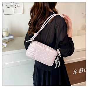 Detail of pink polka dot crossbody bag with 3D cartoon decor and elegant pearl chain