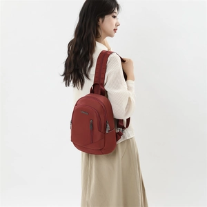 Détail d'un sac à dos en nylon bordeaux avec logo métallique et surface imperméable