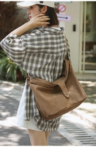Detail of caramel brown canvas crossbody bag with metal buckle on a casual tote