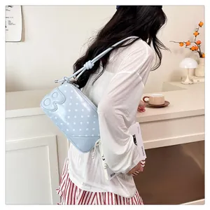 Detail of light blue polka dot crossbody bag with pearl chain and B letter applique