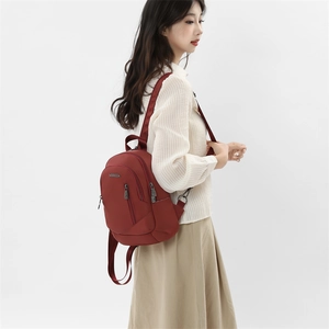 Détail du sac à dos en nylon rouge sur mannequin avec bretelles et logo métallique